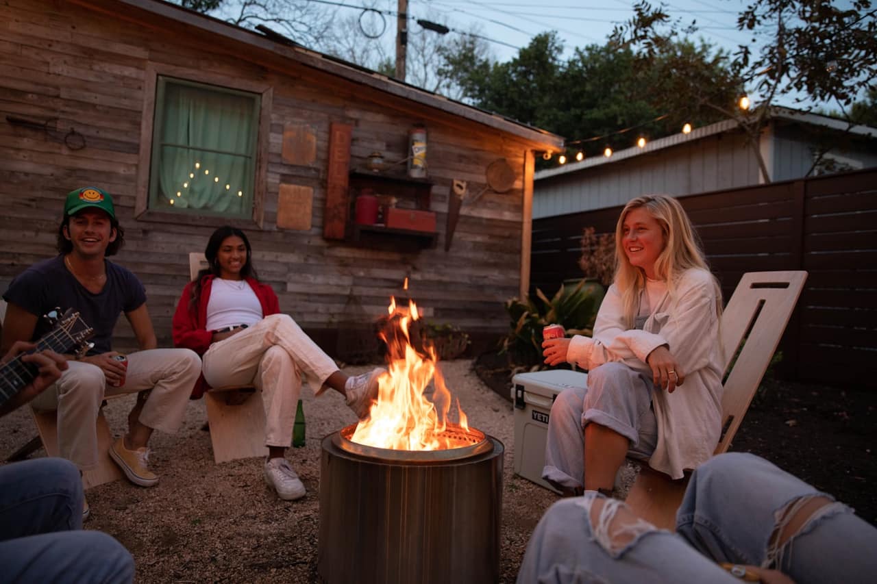 Family and friends relaxing around a backyard fire pit on a warm evening